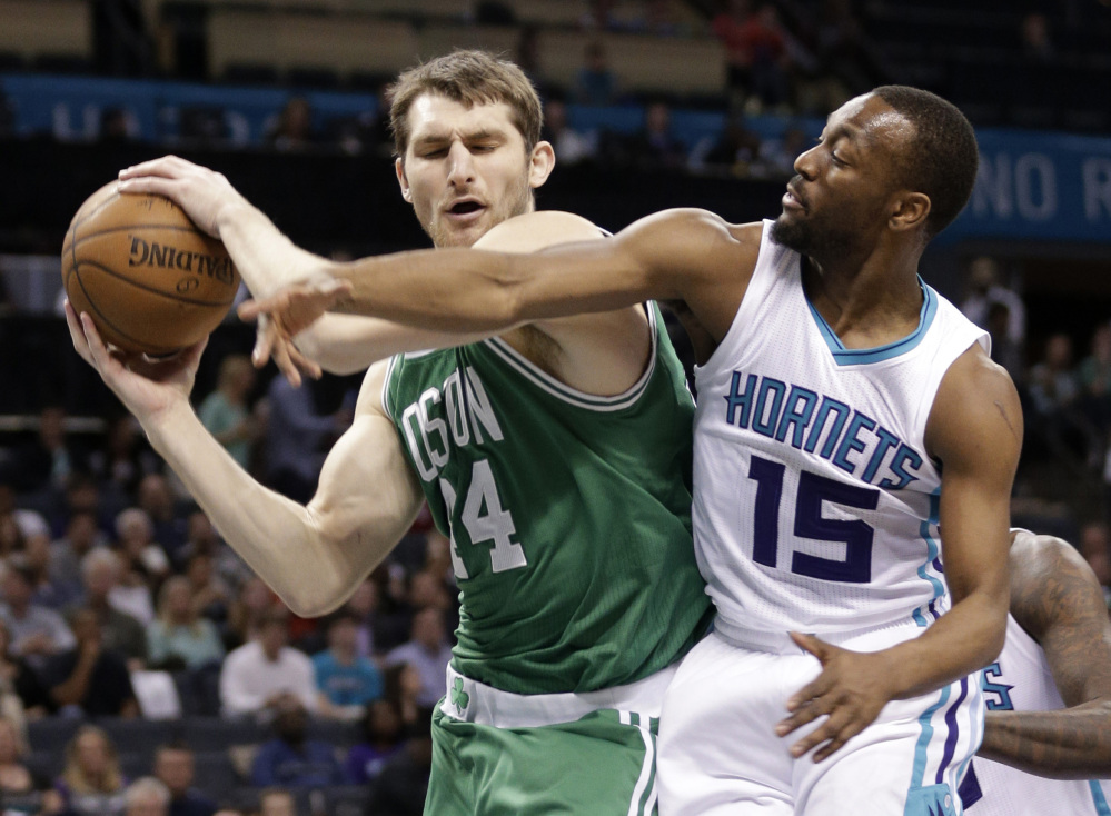 The Celtics’ Tyler Zeller grabs a rebound in front of the Charlotte Hornets’ Kemba Walker during the first half of Monday night’s game in Charlotte, N.C.