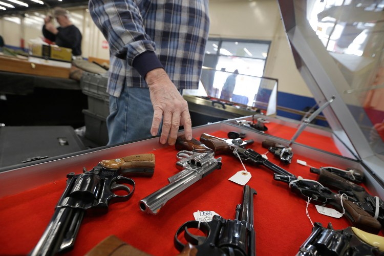A dealer arranges handguns in a display case in advance of a February show at the Arkansas State Fairgrounds in Little Rock. A major U.S. trend survey finds that the number of Americans who live in a household with at least one gun is lower than it's ever been.
