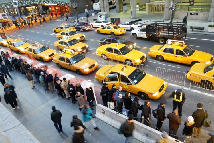 Morning rush hour commuters line up for cabs outside Grand Central Station. City residents have hailed yellow taxis with a whistle and a wave for generations. The Associated Press