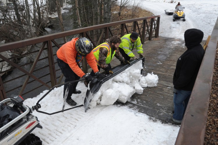 Parks and Recreation maintenance workers empty a sled load of snow from Goose Lake onto a snowless bridge in Anchorage, Alaska. Crews have been moving snow into tunnels, covering bridges and bare spots in the trail in preparation for the ceremonial start of the Iditarod Trail Sled Dog Race. The Associated Press
