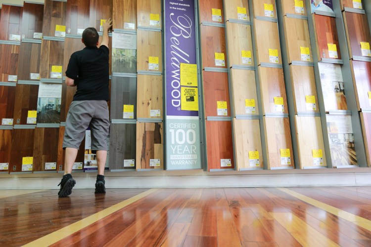 Kiel Skrobacz, an assistant store manager at Lumber Liquidators in Lutz, Fla., sticks yellow sale tags on flooring products recently. The founder and chairman of the company has said that the retailer currently has no plans to stop selling laminate flooring made in China. The Associated Press