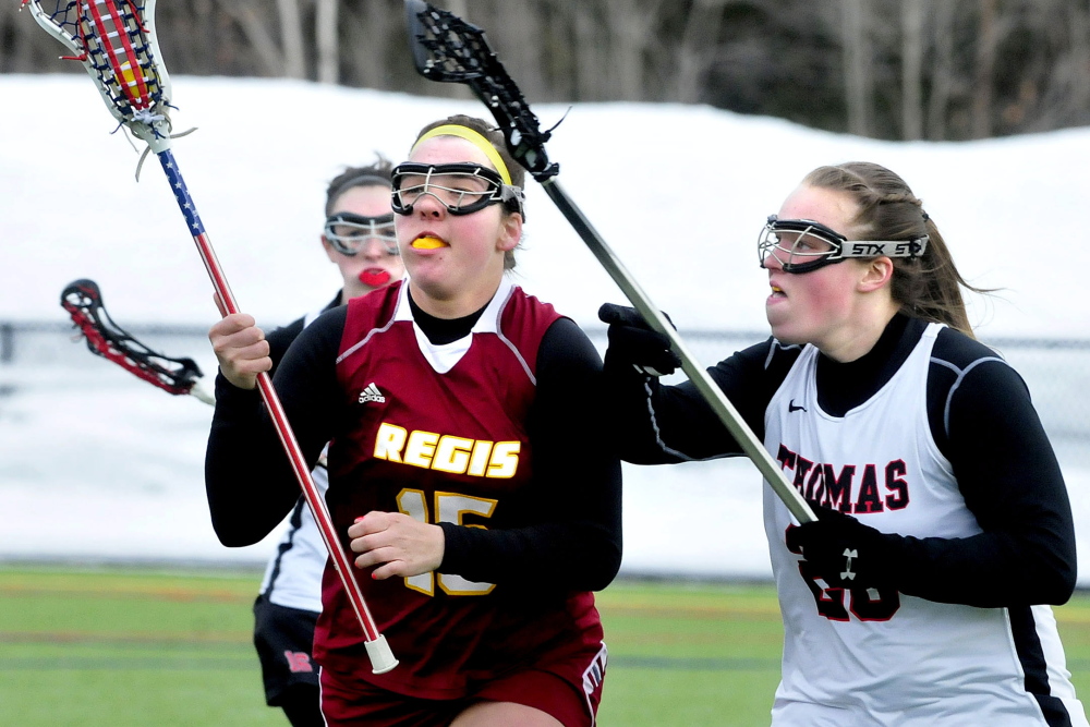 Thomas College’s Sophia LaVallee, left, and Jennifer Day, right, pressure Regis’ Mary Roma during a non-conference women’s lacrosse game Thursday.