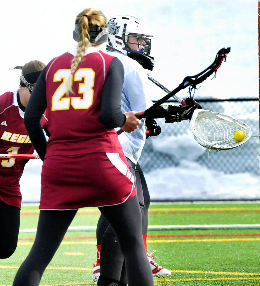 Thomas College keeper Ali McCarthy, middle, makes a save against Regis’ Linsay Bumila, (23) during a women’s lacrosse game Thursday in Watervile.