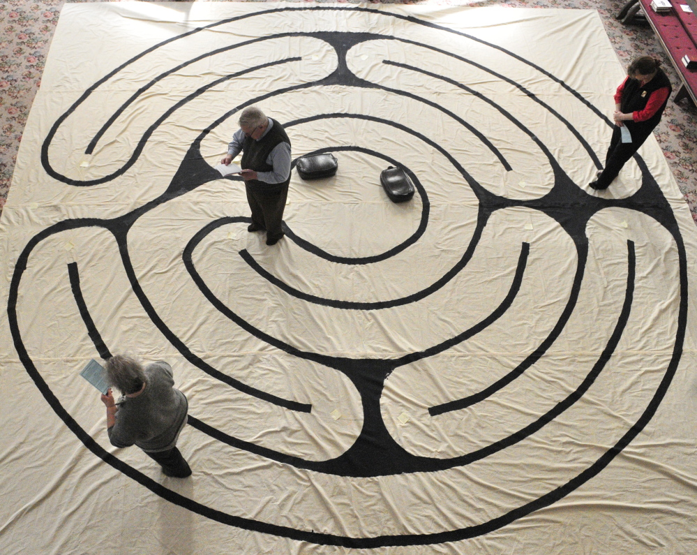 Suzan Katzir, left, the Rev. Jim Gill and Jenifer Lewis walk the labyrinth on Friday in the Winthrop Center Friends Meeting House where the St. Andrew’s Episcopal Church meets.