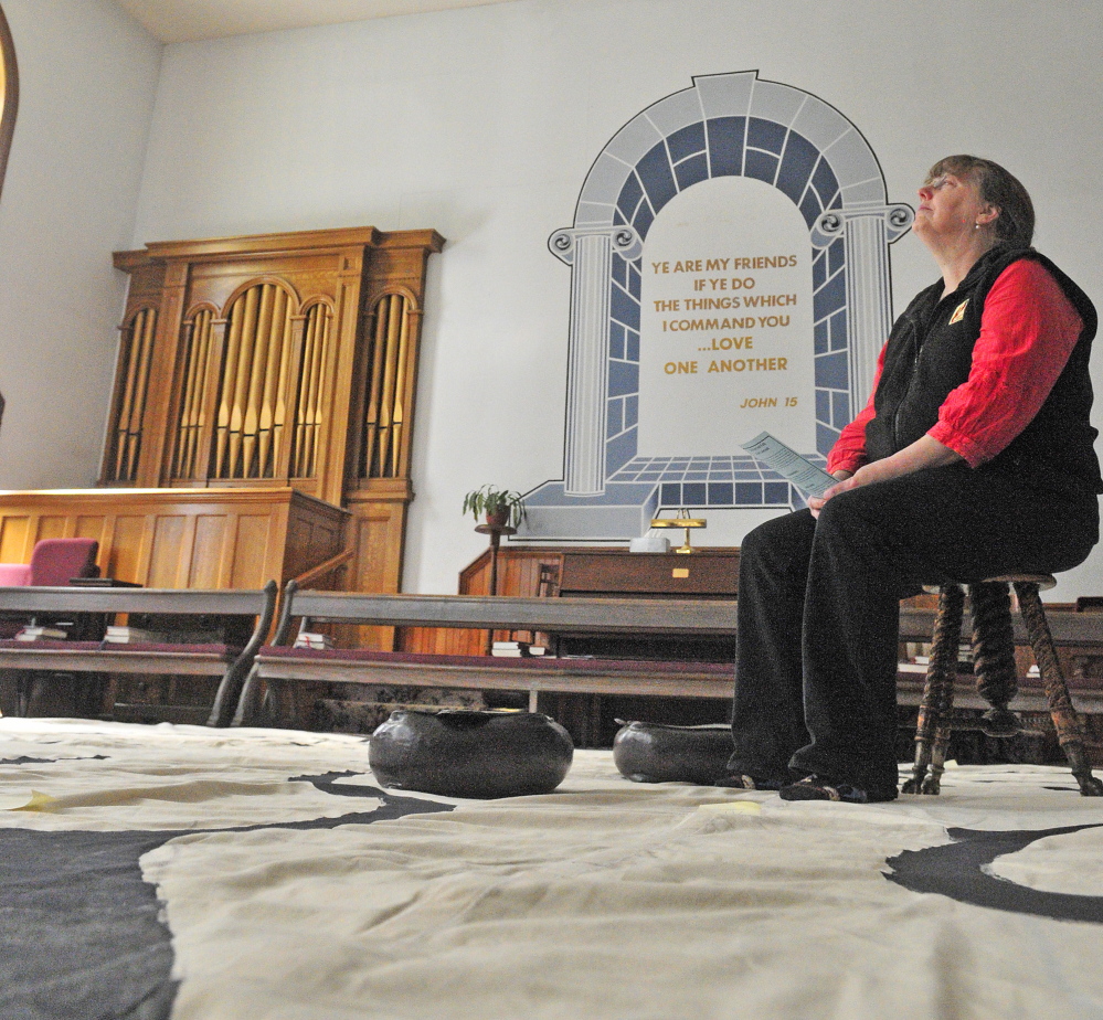 Jenifer Lewis sits on a stool meditating at the center of the labyrinth on Friday in the Winthrop Center Friends Meeting House where the St. Andrew’s Episcopal Church meets.