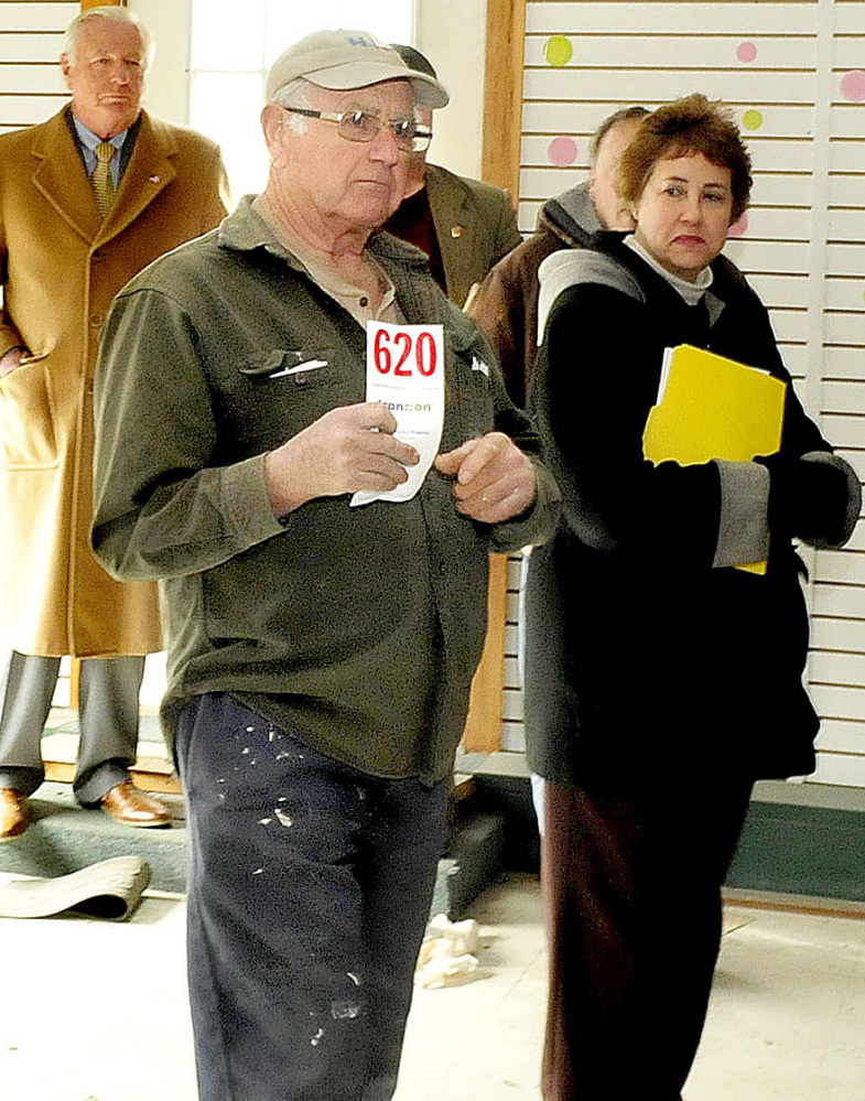 Earl Farris holds up his bidding card after making the winning bid on the former A.L. Weeks & Son business auctioned off in Waterville on Thursday.
