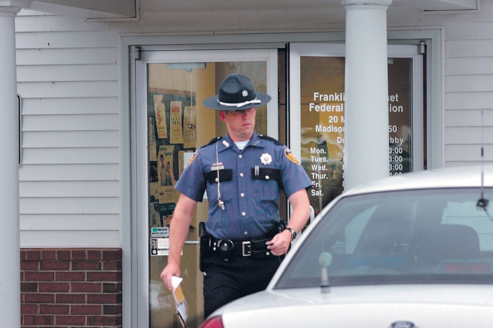 Madison police officer Kevin Hartley returns to his cruiser while investigating an armed robbery at the Franklin Somerset Federal Credit Union in Madison in 2009. Town residents will weigh in on whether to eliminate the town’s police department in June and instead contract with the Somerset County Sheriff’s Department. Staff file photo by David Leaming