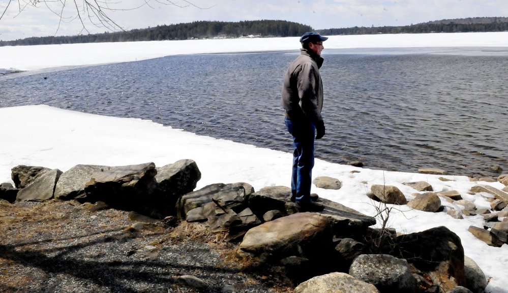 Tim Comeford looks out on Long Pond in Belgrade as ice continues to recede on Sunday. Comeford said the ice usually goes out the third week of April.