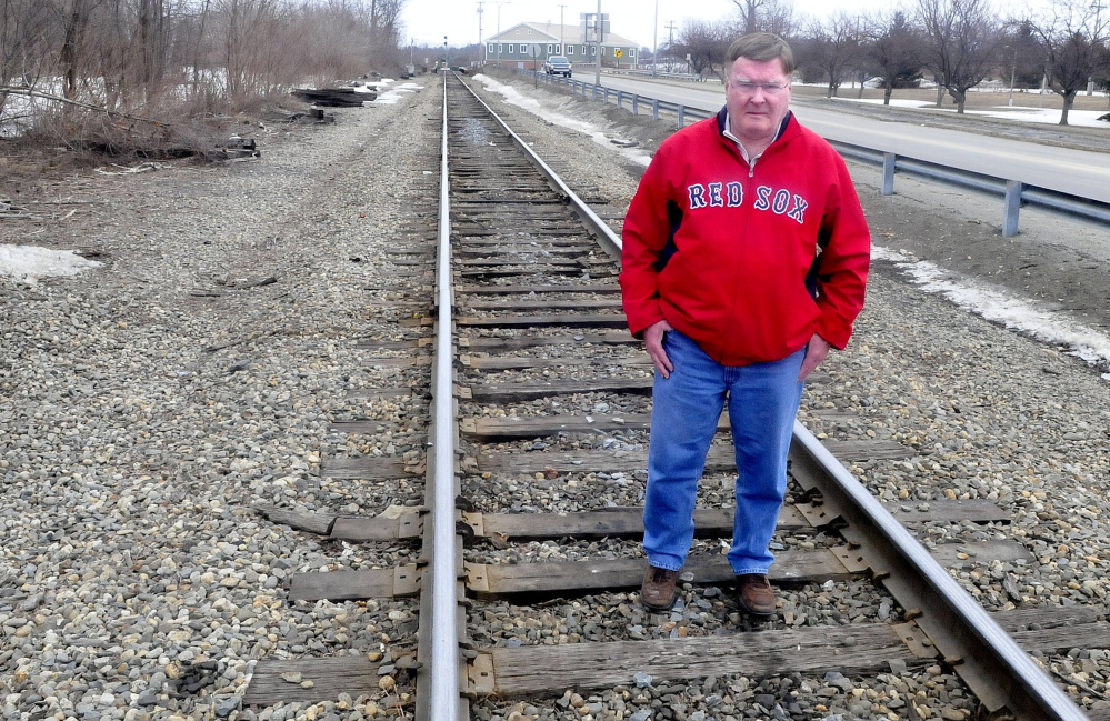 Waterville City Council Chairman Fred Stubbert stands on railroad track where the passenger railroad station used to be in Waterville along Colby Street on Thursday. The City Council will discuss a resolution to restore passenger service.
