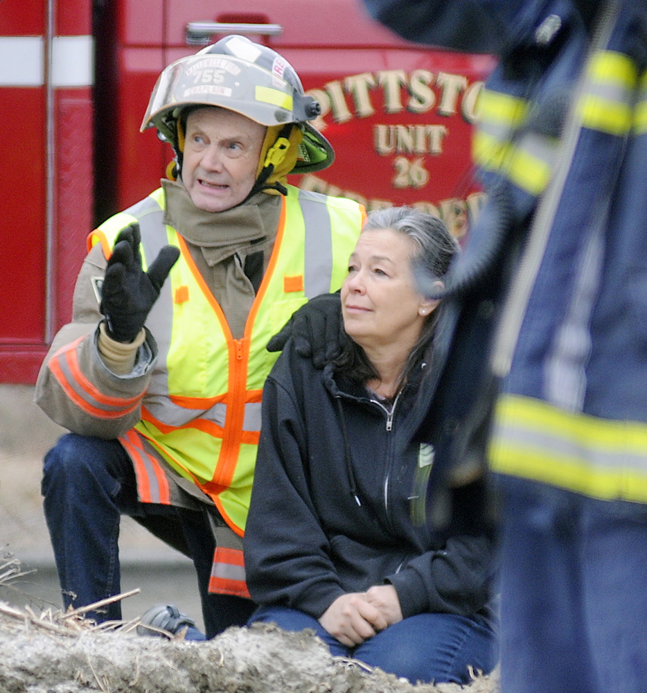 Hallowell Fire Department Chaplain Peter Inchombe comforts Grace Montalbo Wednesday as firefighters battle a blaze at her Farmingdale home.