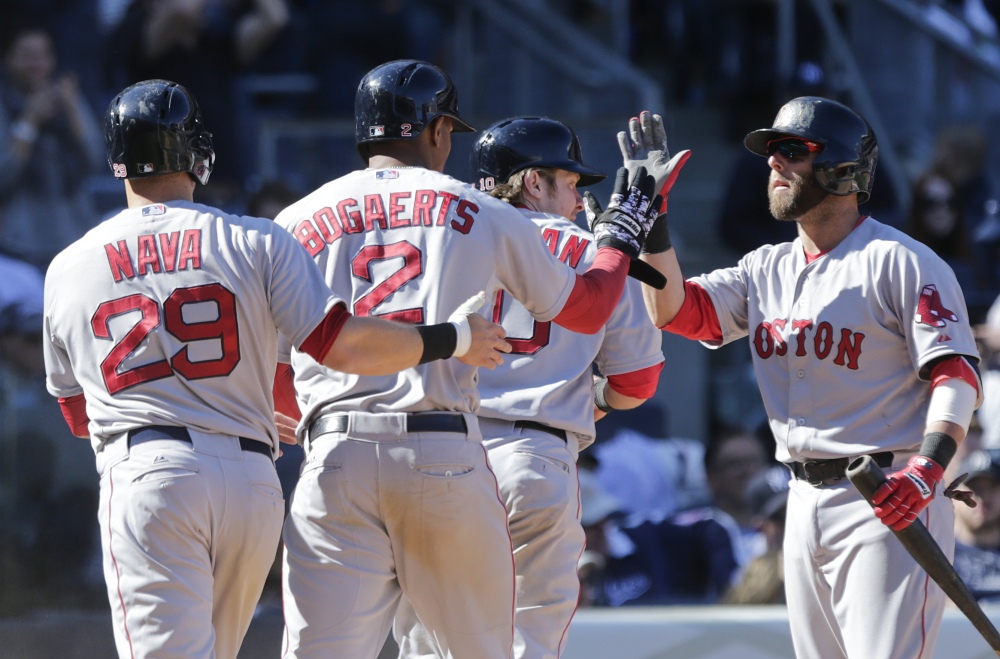 Boston Red Sox’s Dustin Pedroia, right, celebrates with teammates Daniel Nava, 29, Xander Bogaerts, 2, and Ryan Hanigan, 10, after they scored on a double by Brock Holt during the eighth inning of a baseball game Saturday in New York.