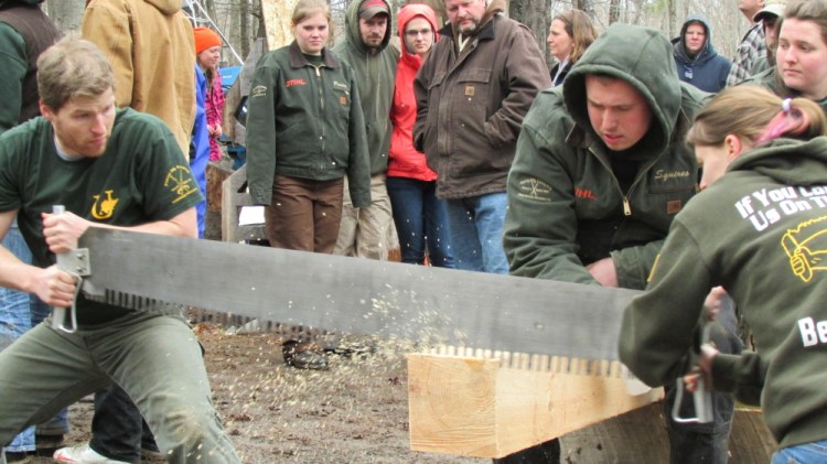 Unity College students Joe Ranzoni and Lauren Souther saw through a beam at the annual Mud Meet collegiate woodsmen competition at Colby College in Waterville Saturday afternoon. Holding the beam is Unity student Matt Squires.