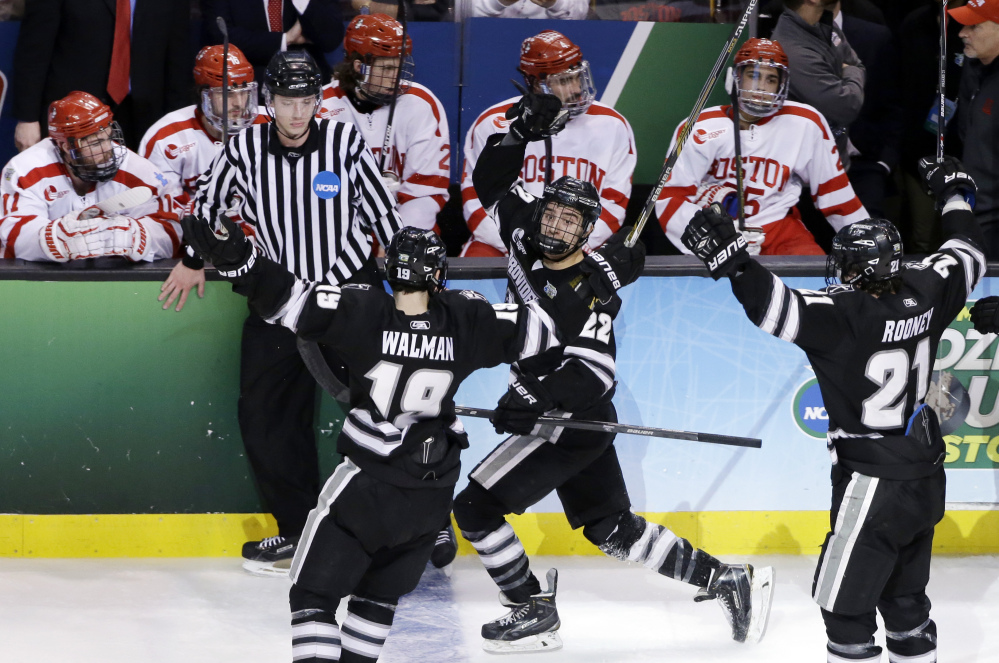 Providence forward Brandon Tanev (22) celebrates with teammates Jake Walman (19) and Kevin Rooney (21) after his go-ahead goal against Boston University during the third period Saturday of the NCAA men’s Frozen Four hockey championship game in Boston. Providnece won 4-3.