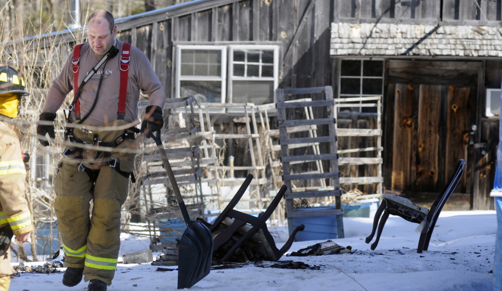 Firefighters carry a shovel back to an engine after extinguishing furniture that burned in the room of a home in Whitefield on Sunday. Several departments responded to the blaze that caused minimal damage to the home, according to firefighters.