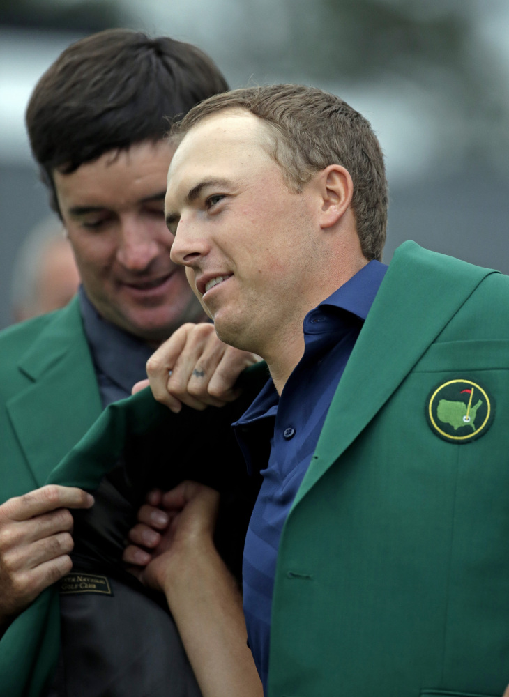 Bubba Watson helps Jordan Spieth put on his green jacket after Spieth won the Masters on Sunday in Augusta, Ga.