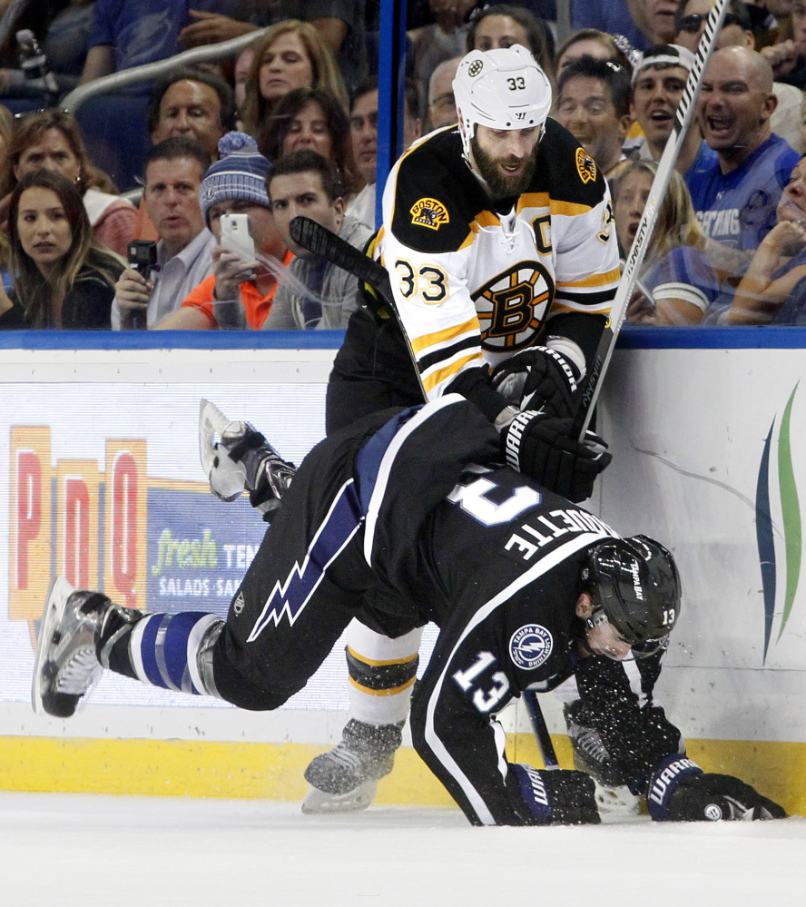 Tampa Bay Lightning center Cedric Paquette (13) goes down after Boston Bruins defenseman Zdeno Chara (33) fights off a check during the second period Saturday in Tampa, Fla.