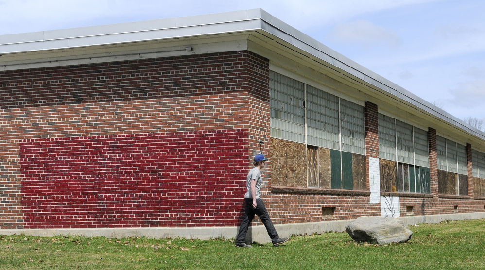 Tyler Lessard, 15, walks around the former Hodgkins Middle School in Augusta to the nature trails behind it on Tuesday. The Augusta Housing Authority and a local developer have proposed to redevelop the abandoned building into elderly housing.