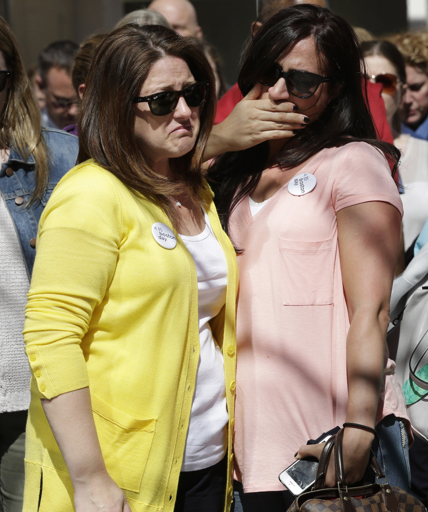 Jenna Dziedzic, left, stands with Sabrina Dellorusso, both of Boston, following a moment of silence at one of two blast sites near the finish line of the Boston Marathon on Wednesday. The women were close to a blast site near the finish line of the Boston Marathon in 2013 where a friend, Roseann Sdoia, lost a limb during the explosion.
