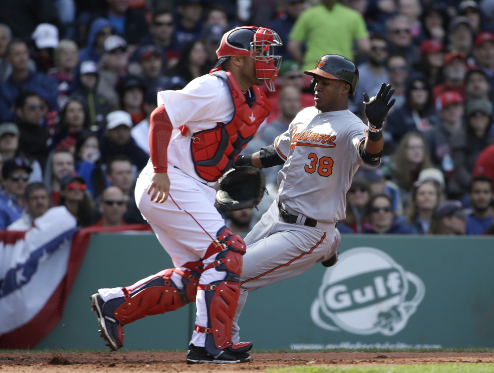 Baltimore Orioles’ Jimmy Paredes, right, scores on a three-run double by teammate Adam Jones as Boston Red Sox catcher Sandy Leon, left, waits for the ball in the sixth inning of a baseball game Sunday in Boston.