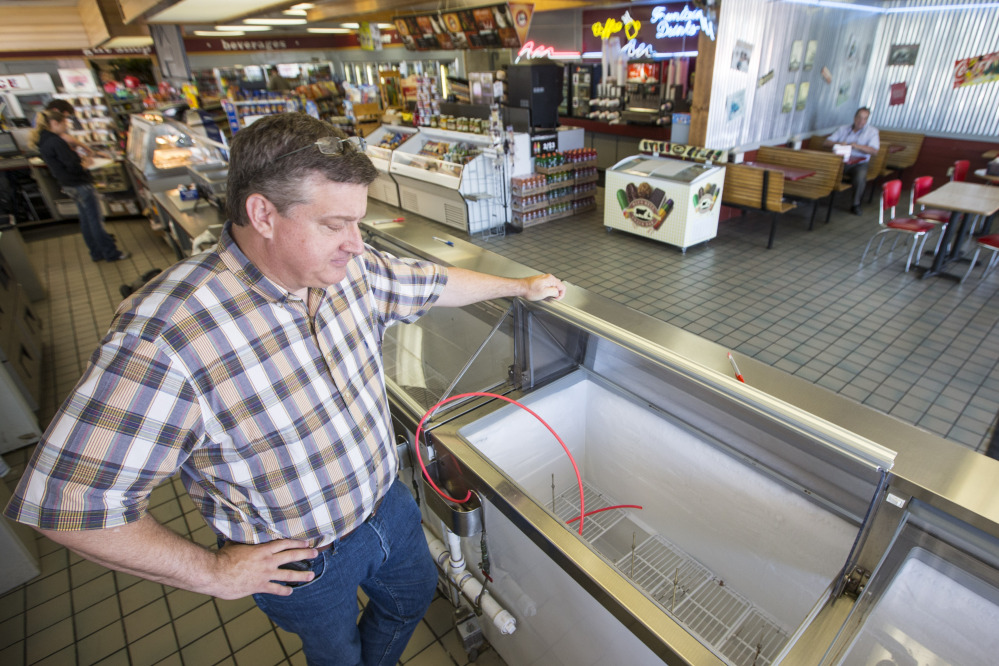 Brett Smith, owner of Scoops Ice Cream, looks over the empty ice cream case on Tuesday in Brenham, Texas.