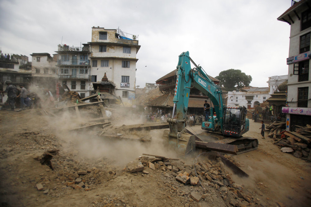 A crane removes debris from the site of a building that collapsed in an earthquake in Kathmandu, Nepal, on Saturday.