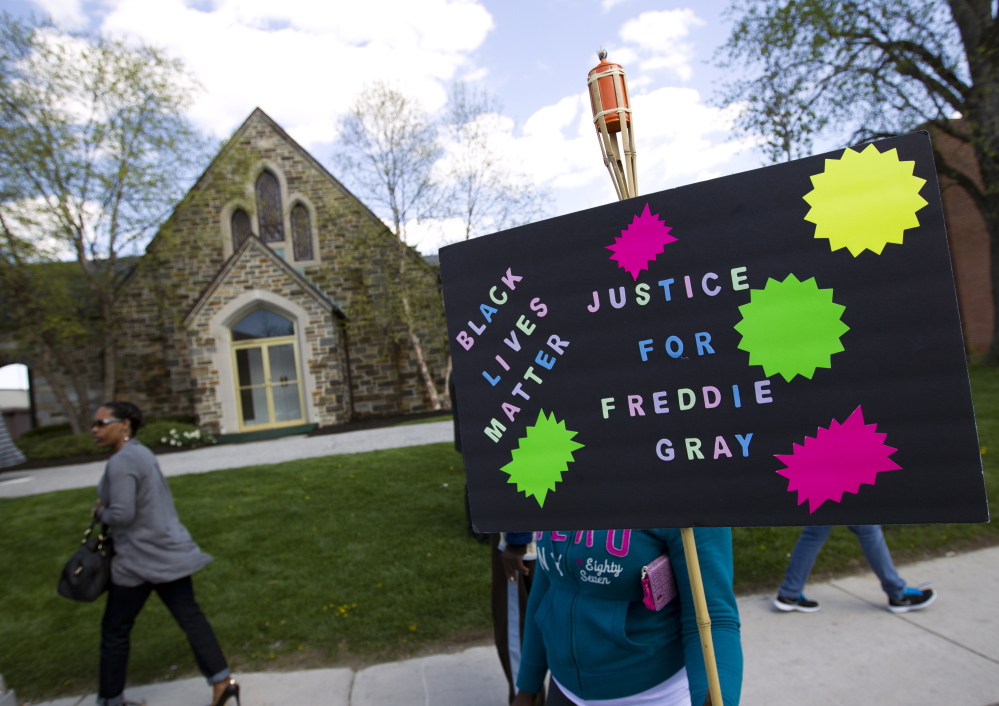 Demonstrators hold up signs outside the funeral home during Freddie Gray’s wake in Baltimore, Md., on Sunday. Gray died from spinal injuries a week after he was arrested.