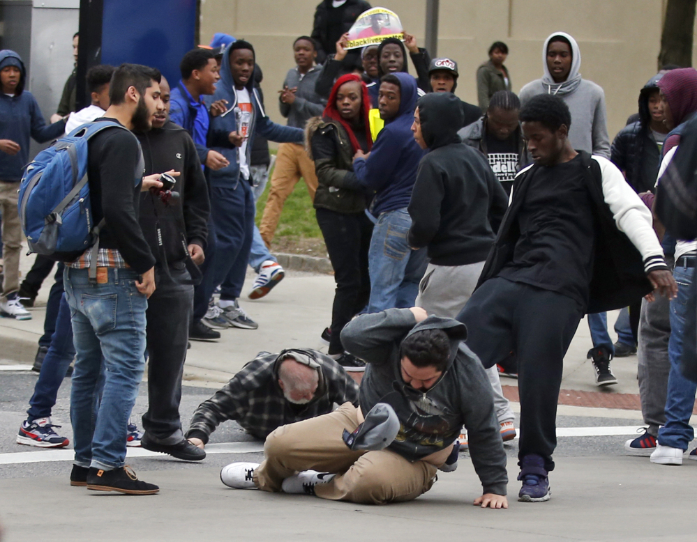 A man is kicked as he attempts to get up after being knocked down, following a march to City Hall for Freddie Gray on Saturday in Baltimore.