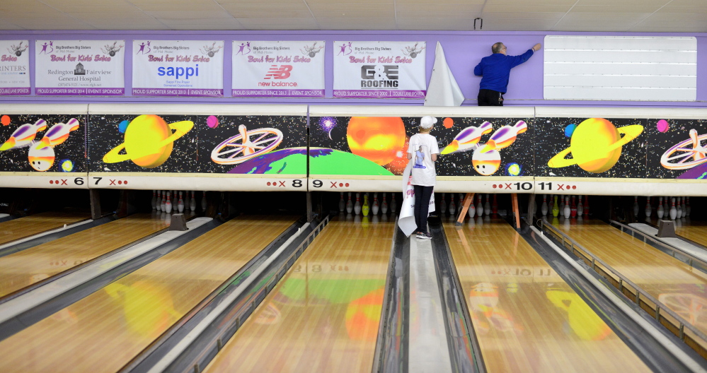 Bill Farnum, SpareTime Recreation manager, pulls signs from the wall over the bowling lanes at the alley on West River Road in Waterville on Tuesday as the bowling center prepares to cease operations Wednesday.