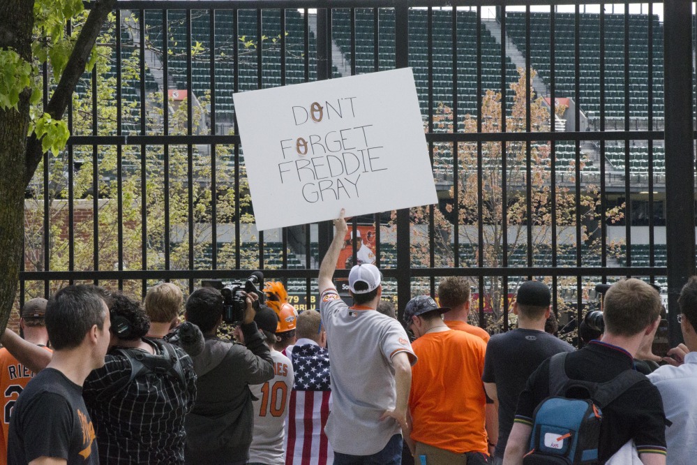 Brendan Hurson, of Baltimore, holds a sign as fans view a baseball game between the Baltimore Orioles and Chicago White Sox on Wednesday from outside of Oriole Park at Camden Yards in Baltimore.