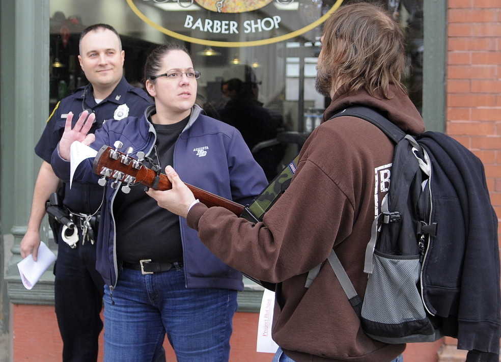 Augusta Police Detective Tori Tracy and Officer Jesse Brann speak with a man Wednesday playing guitar on Water Street while canvassing. Law enforcement officers were notifying people of a larger police presence planned in the future in crime “hot spots” while soliciting input on how to combat crime.