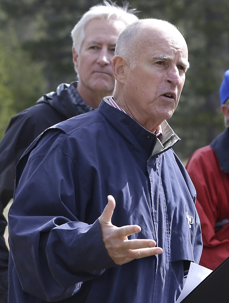 California Gov. Jerry Brown, front, in Echo Summit, Calif., on Wednesday, answers a question concerning the executive order he signed that requires mandatory water restrictions to reduce usage by 25 percent.