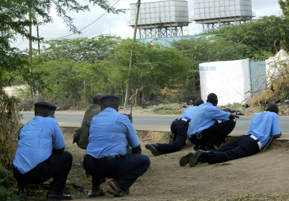 Kenyan police officers take cover outside the Garissa University College during an attack by gunmen Thursday. Islamist militants shot indiscriminately in campus hostels, killing 147.
