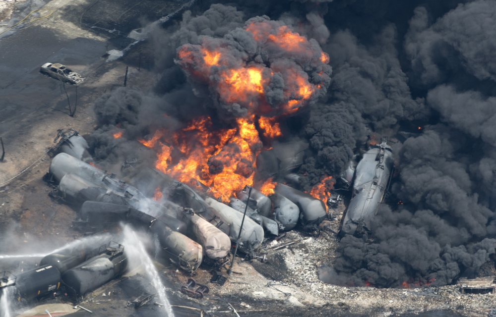 Smoke and flames billow from derailed railway cars carrying crude oil in downtown Lac-Megantic, Quebec, on July 6, 2013. Families of the 47 people killed in the disaster stand to split nearly $86 million as compensation.