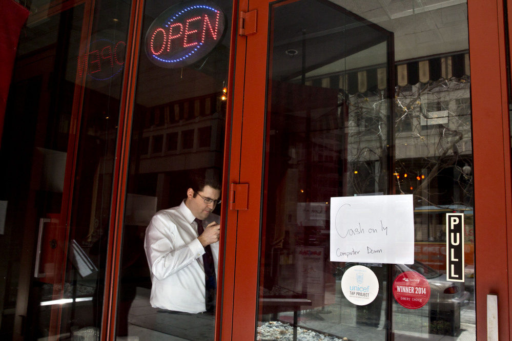 A man checks his cellphone in a restaurant with a sign advertising that the computer is down, as power returns after a brief power outage Tuesday in Washington.