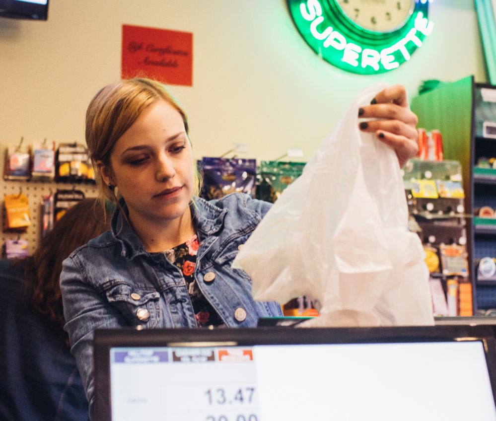 Colucci’s cashier Ayriel Chase prepares a plastic bag for a customer. Some shoppers carry items out in their hands to avoid a fee.