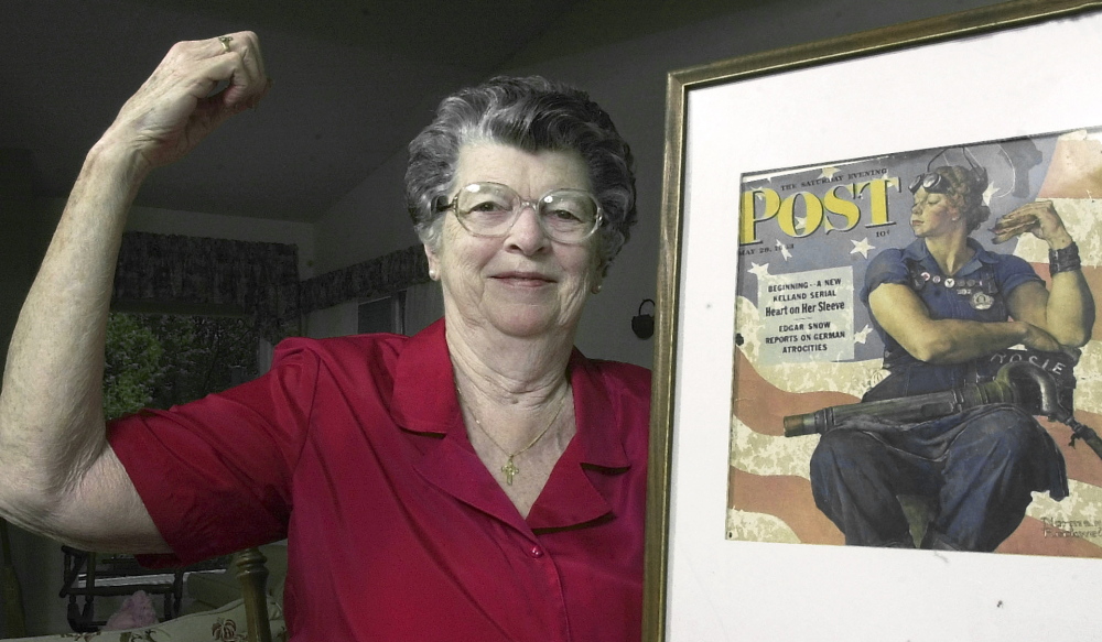 In a 2002 photo,  Mary Doyle Keefe poses with the iconic 1943 cover of the Saturday Evening Post for which she  modeled as Rosie the Riveter in the Norman Rockwell painting.