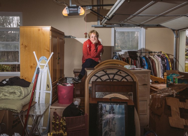 FALMOUTH, ME - APRIL 23: Lisa Arens sits atop items for her yard sale, which she had to bring inside her garage after it began raining in Falmouth, ME on Thursday, April 23, 2015. Arens and her husband are moving to Lake Worth, Florida. (Photo by Whitney Hayward/Staff Photographer)