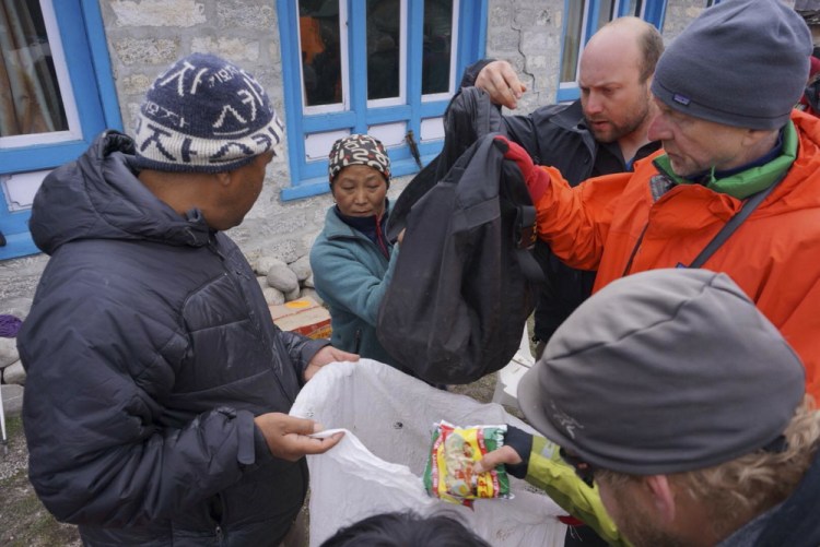 Doug Bruns, right, and fellow trekkers, hand out tarps and food Wednesday to residents of Thame, Nepal, a remote mountain village that was leveled by Saturday's earthquake.
Photo by Rick Nooft