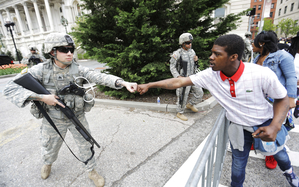 Brandon Payton, right, of Baltimore, fist-bumps a National Guardsman standing outside City Hall as protesters march by to demonstrate the police-custody death of Freddie Gray on Thursday in Baltimore. Baltimore police say they have turned over their criminal investigation to a prosecutor who will decide whether charges are warranted in the death of Gray.
