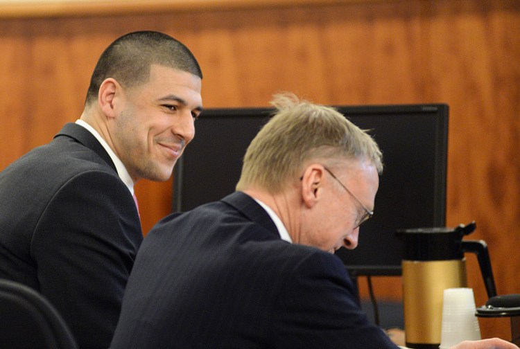 Former New England Patriots tight end Aaron Hernandez smiles with attorney Charles Rankin in the courtroom during the jury's first full day of deliberations in Hernandez' murder trial, on April 8. The Associated Press