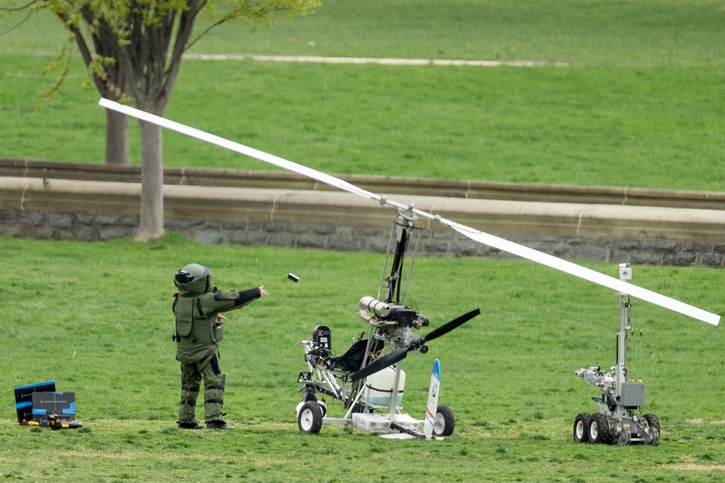 A member of a bomb squad pulls something off a "gyrocopter" and throws it after police arrested the man who steered the one-person helicopter onto the West Lawn of the U.S. Capitol Wednesday. The small vehicle at right is a robot designed to investigate potential bombs. The Associated Press