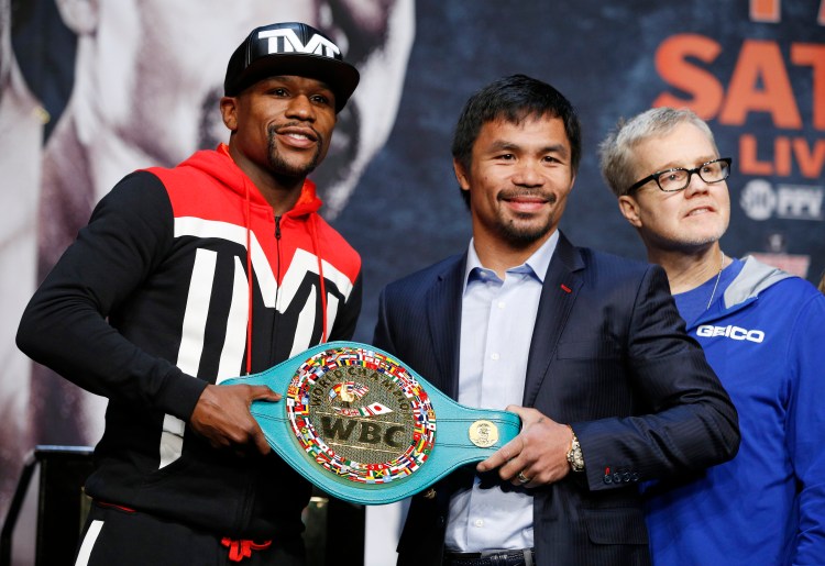 Boxers Floyd Mayweather Jr., left, and Manny Pacquiao pose with a WBC belt during a press conference Wednesday, April 29, 2015, in Las Vegas. Mayweather will face Pacquiao in a welterweight title fight in Las Vegas on May 2. At right is Freddie Roach, Pacquiao's trainer. 