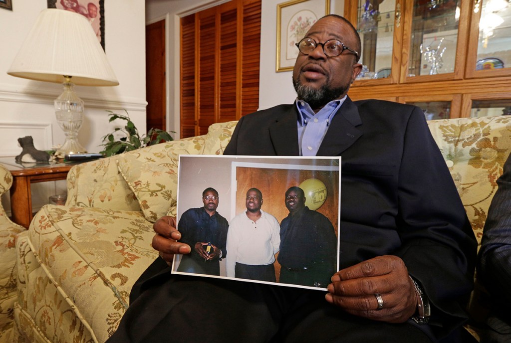 Anthony Scott holds a photo of himself, center, and his brothers Walter Scott, left, and Rodney Scott, at his home near North Charleston, S.C., Wednesday. Below: A closeup of Walter Scott in the same photo. The Associated Press