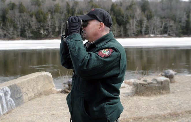 Marine Patrol Officer Clint Thompson scans the Kennebec River in Hallowell in April while searching for the remains of a woman who reportedly went under the ice in Augusta on March 21.