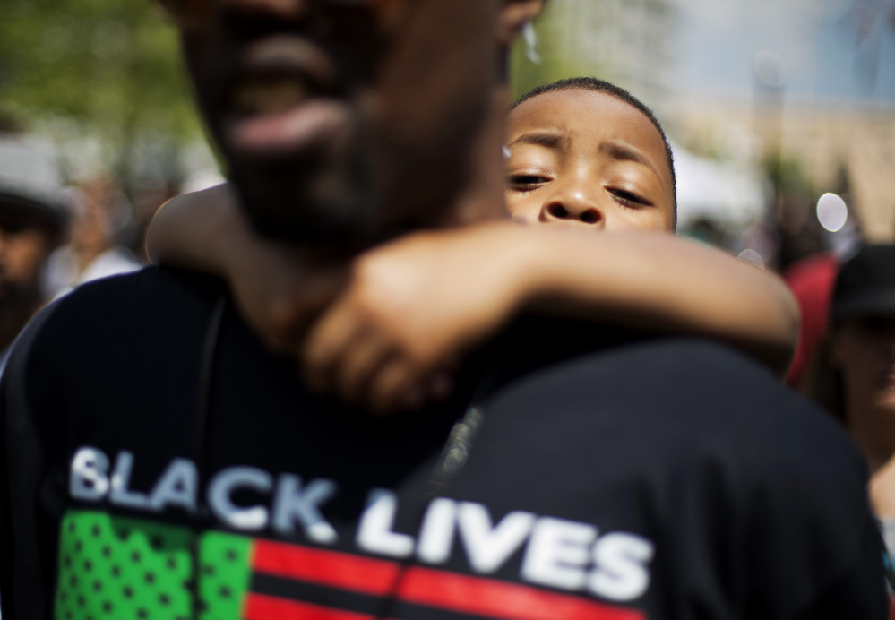 Devonte Reed, 5, right, looks over the shoulder of James Watson, both of Baltimore, while attending a demonstration at City Hall the day after charges were announced against the police officers involved in Freddie Gray’s death on Saturday in Baltimore.