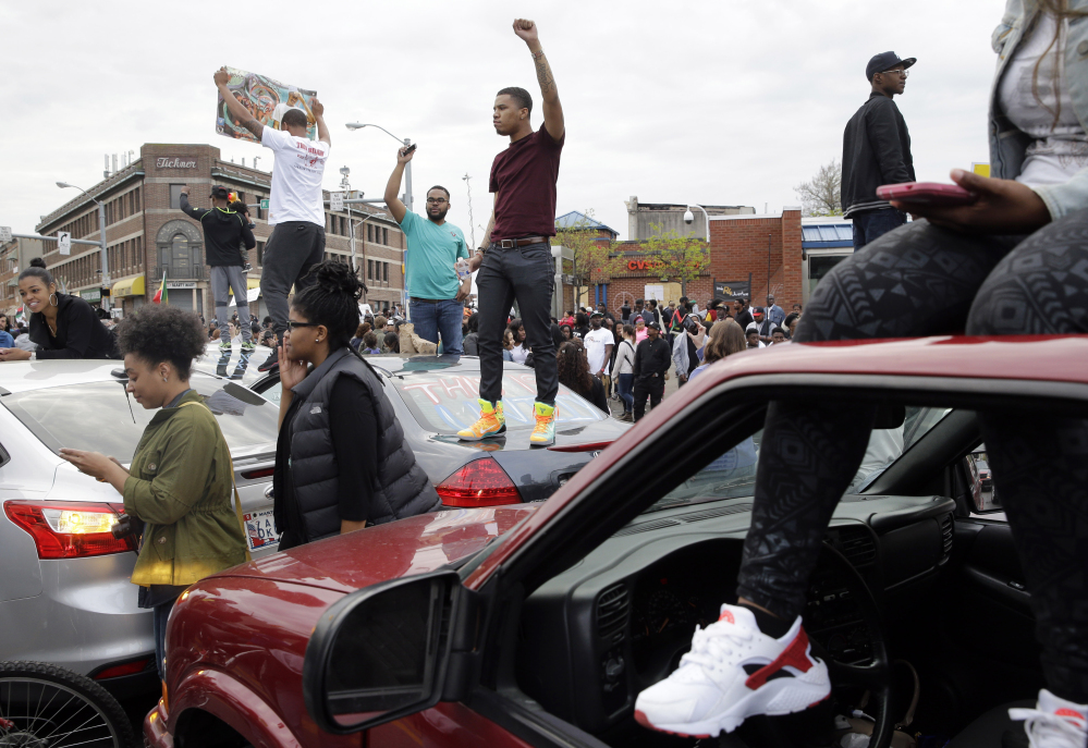Protesters stand on cars near the intersection of North Avenue and Pennsylvania Avenue in Baltimore on Friday, the day of the announcement of charges against the police officers involved in Freddie Gray’s arrest.