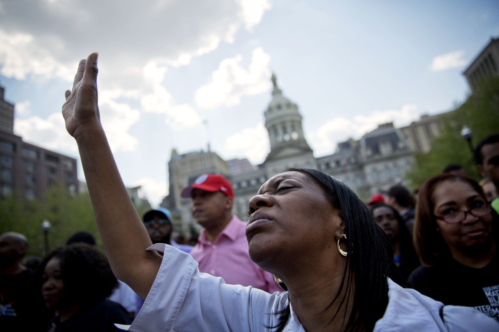 Patricia Freeman prays during a rally in front of City Hall, Sunday in Baltimore.