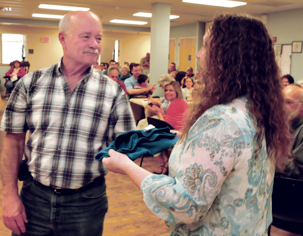 Mid-Maine Homeless Shelter volunteer coordinator Cindy Burns presents a shirt to volunteer John Maddux on Sunday in recognition for his time and effort at the Waterville facility. The presentation took place during a volunteer celebration and annual meeting.