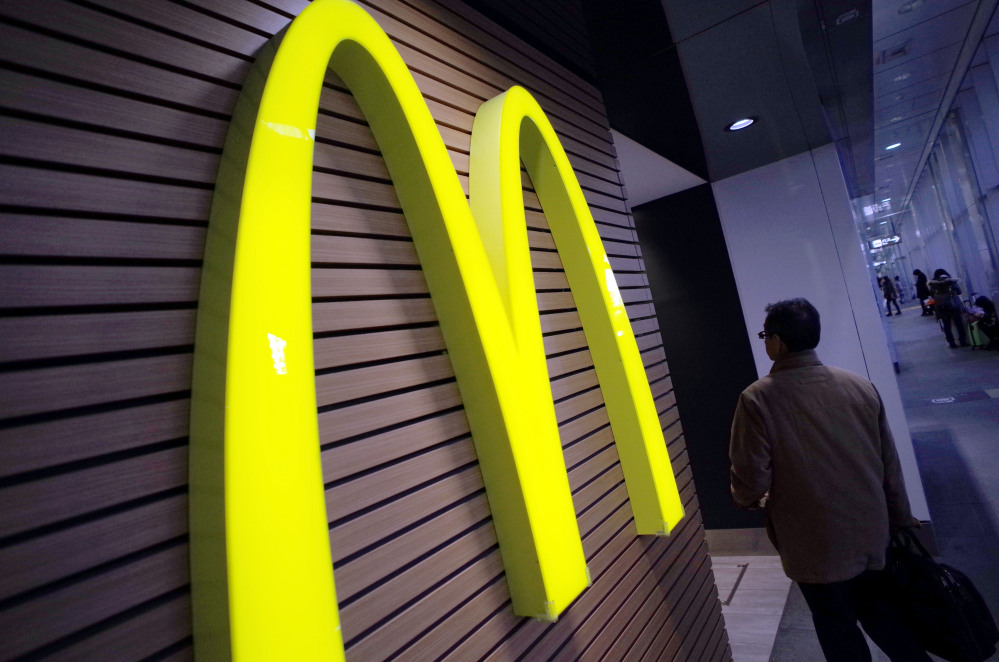 In this Dec. 17, 2014 file photo, a man walks by a McDonald’s logo in front of its restaurant in Tokyo.