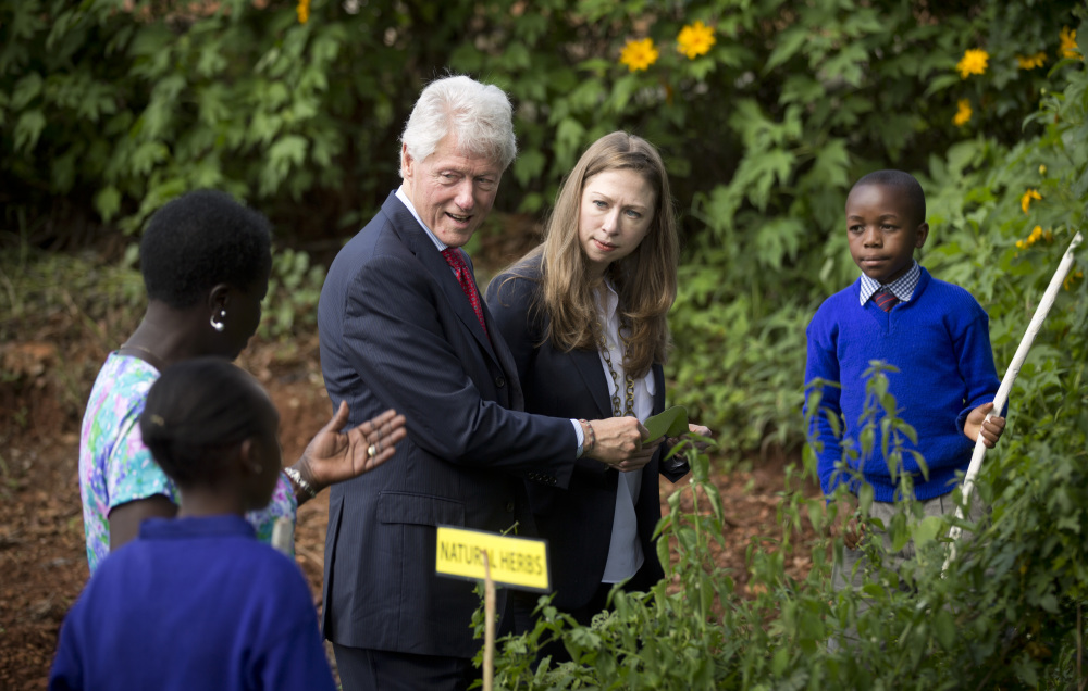 Former President Bill Clinton, center-left, and daughter Chelsea Clinton, center-right, are shown around a herb garden by pupils and staff of the Farasi Lane Primary School in Nairobi, Kenya Friday.